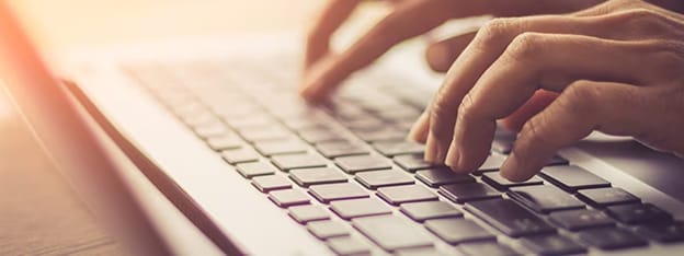 Gros plan de mains tapant sur le clavier d'un ordinateur portable, représentant les opérations de maintenance de routine pour un PC propre
