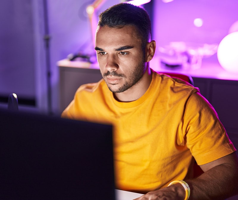 Un homme est assis devant un ordinateur portable et fait des recherches sur le navigateur Tor et sur la manière dont il est utilisé pour accéder au Dark Web.