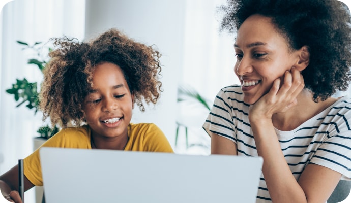 Une jeune fille avec sa mère souriante regardant un ordinateur portable.